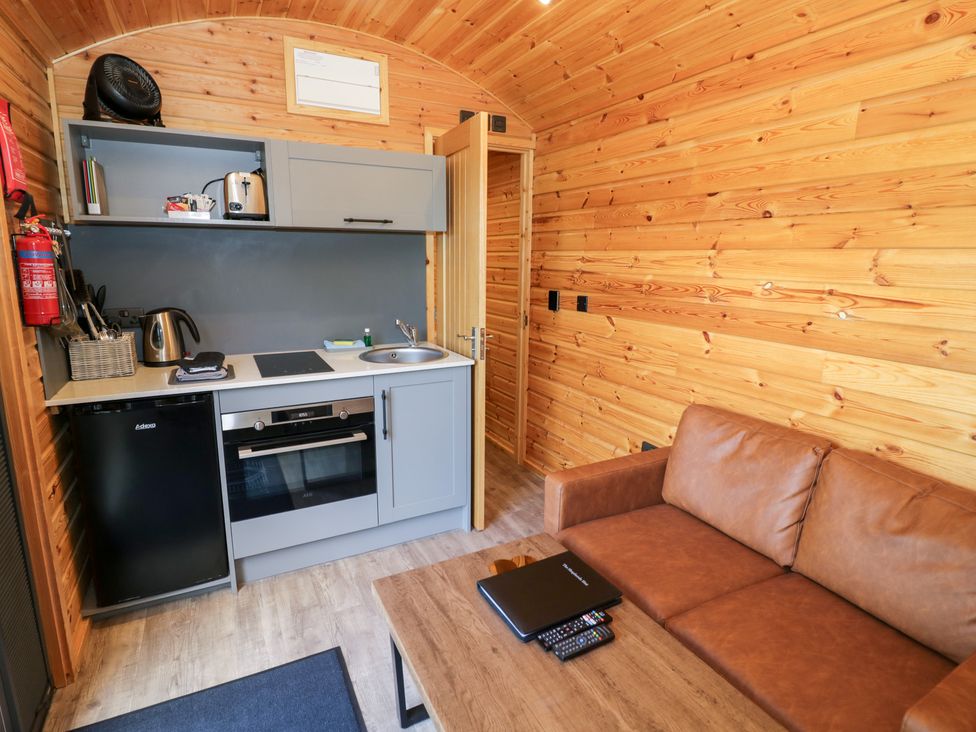 A kitchen area with appliances and a sofa at The Shepherds Hut at Bridge Lake Farm & Fishery Chacombe