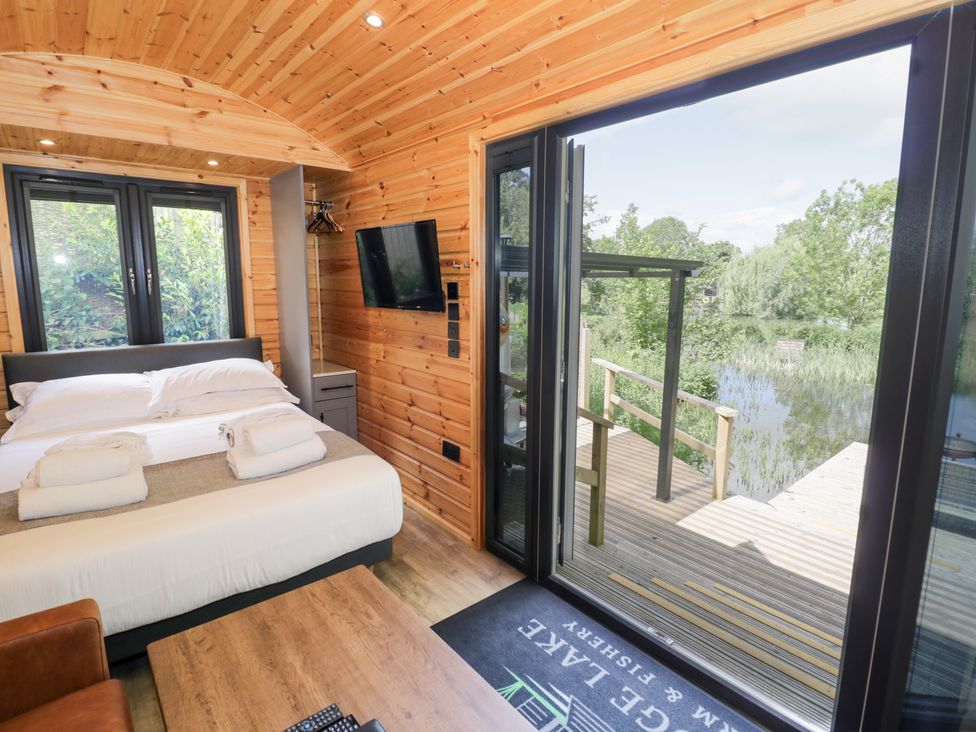 A bedroom with a bed and sliding door at The Shepherds Hut at Bridge Lake Farm & Fishery Chacombe