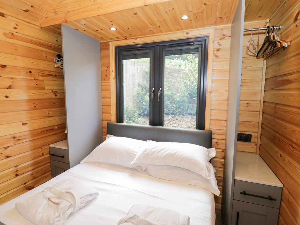 A bedroom with a bed and window at The Shepherds Hut at Bridge Lake Farm & Fishery Chacombe