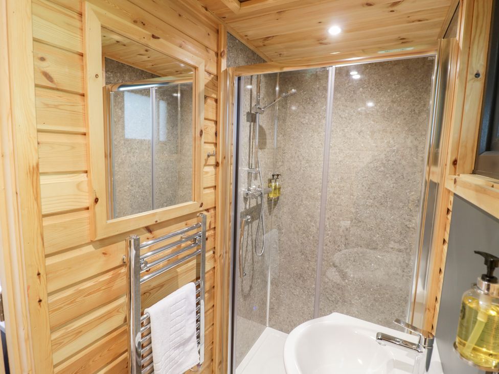 A bathroom with a shower and sink at The Shepherds Hut at Bridge Lake Farm & Fishery Chacombe