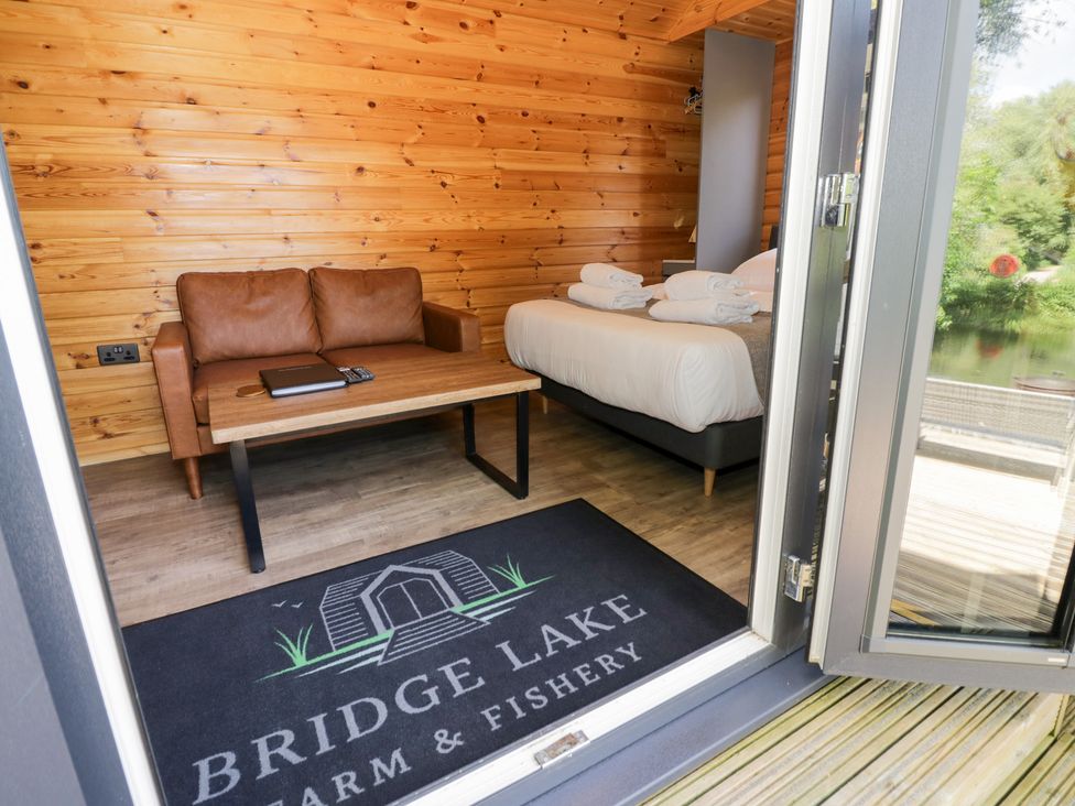 An indoor space with a sofa and a bed at The Shepherds Hut at Bridge Lake Farm & Fishery Chacombe