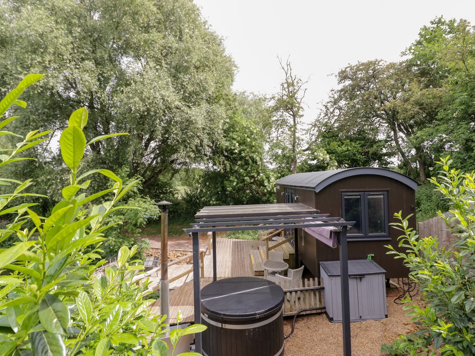 An outdoor area with a hot tub and seating at The Shepherds Hut at Bridge Lake Farm & Fishery Chacombe