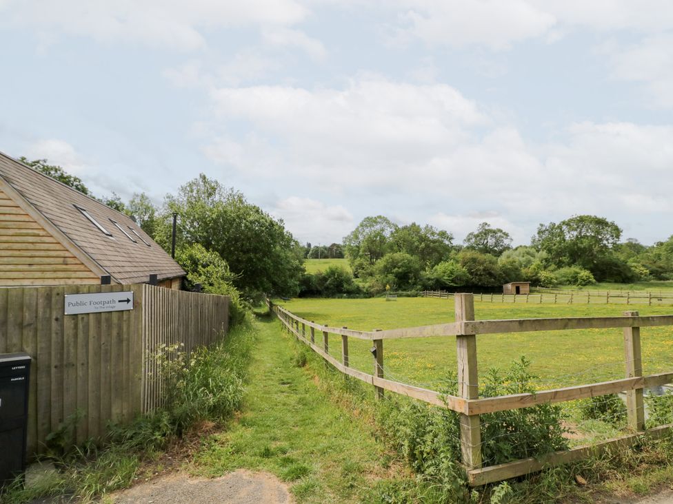 A pathway leading to a field near a building at The Shepherds Hut at Bridge Lake Farm & Fishery Chacombe