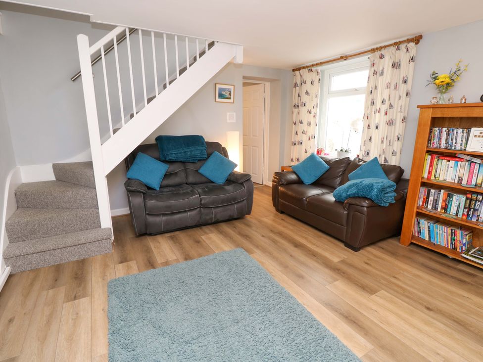 A living room with a sofa, rug, and bookshelf at Willow Cottage in Ventnor