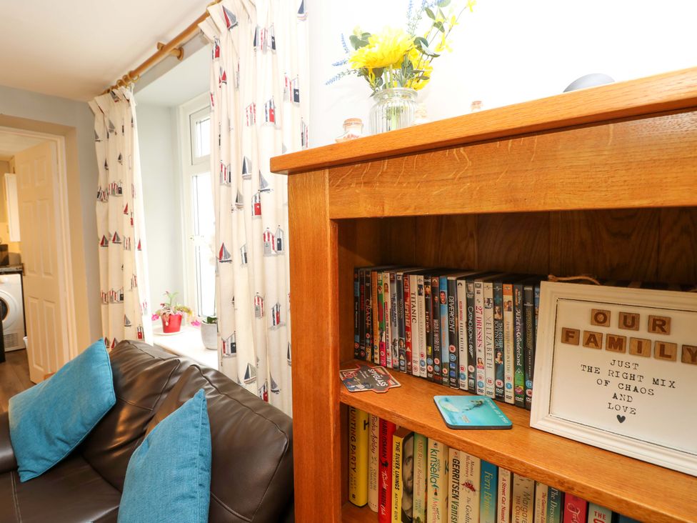 A living room with a bookshelf and flowers at Willow Cottage in Ventnor
