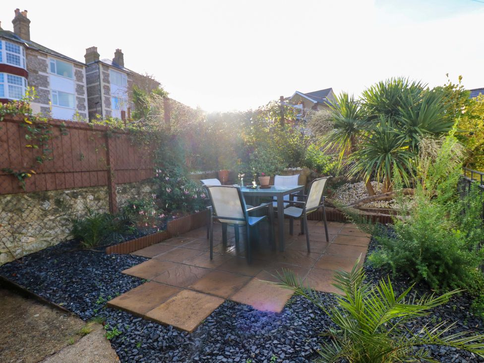 A garden with a table and chairs surrounded by plants at Willow Cottage in Ventnor