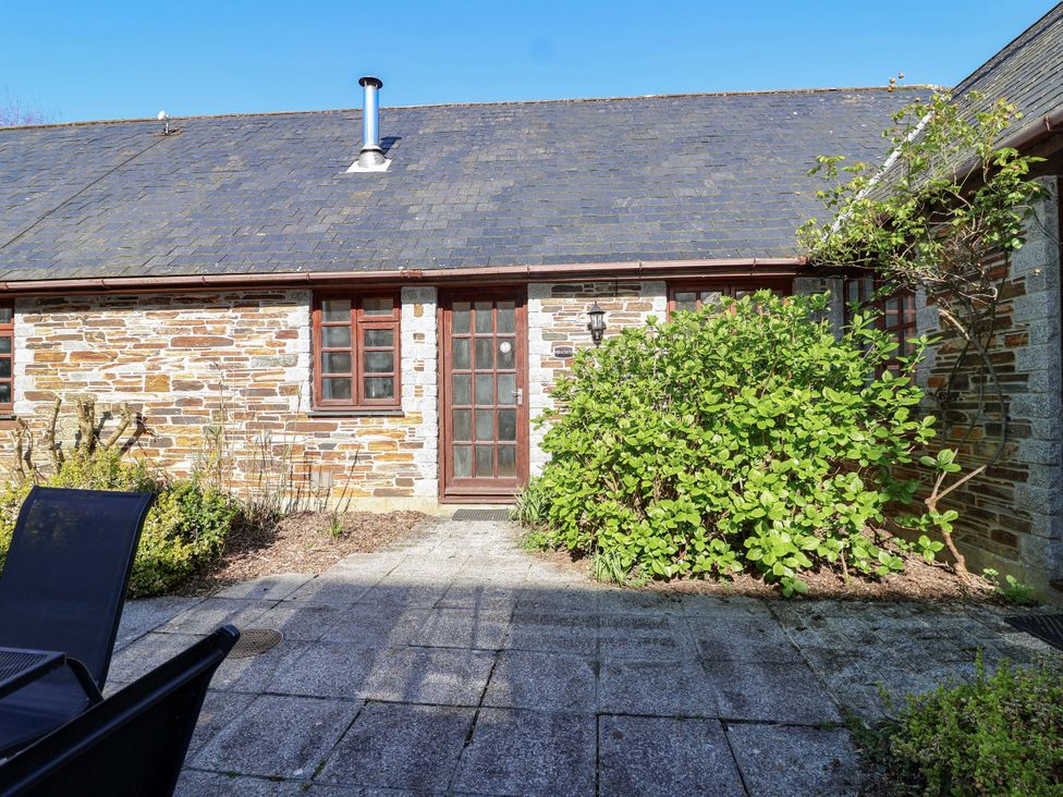 An outdoor view of a stone wall building with a door and pathway at Bracken Cottage St Tudy