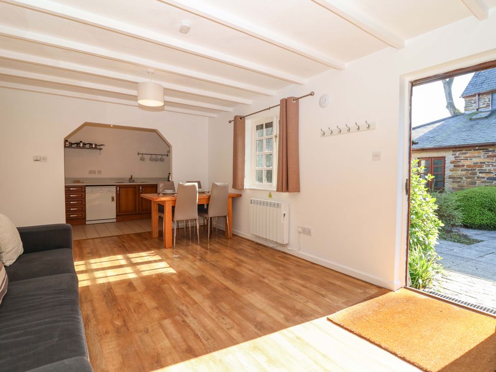 A living room with a kitchen area and seating at Bracken Cottage St Tudy
