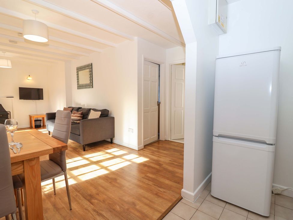 A living room with a refrigerator and dining area at Bracken Cottage St Tudy