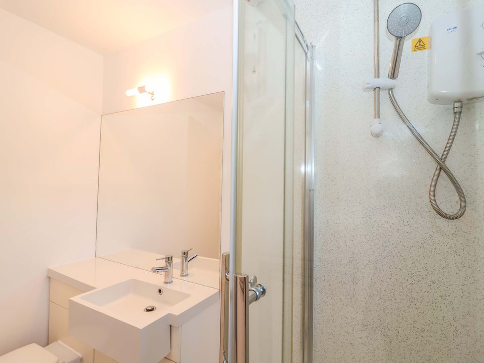 A bathroom with a sink, mirror, shower, and toilet at Bracken Cottage St Tudy