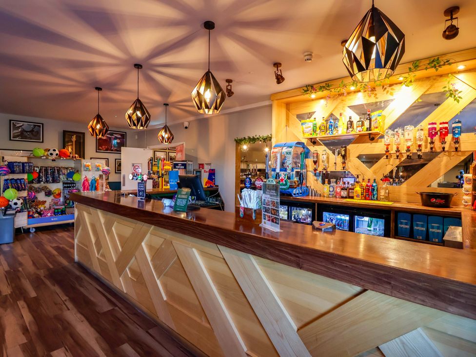 A bar area with a counter and shelves of drinks at Bracken Cottage St Tudy