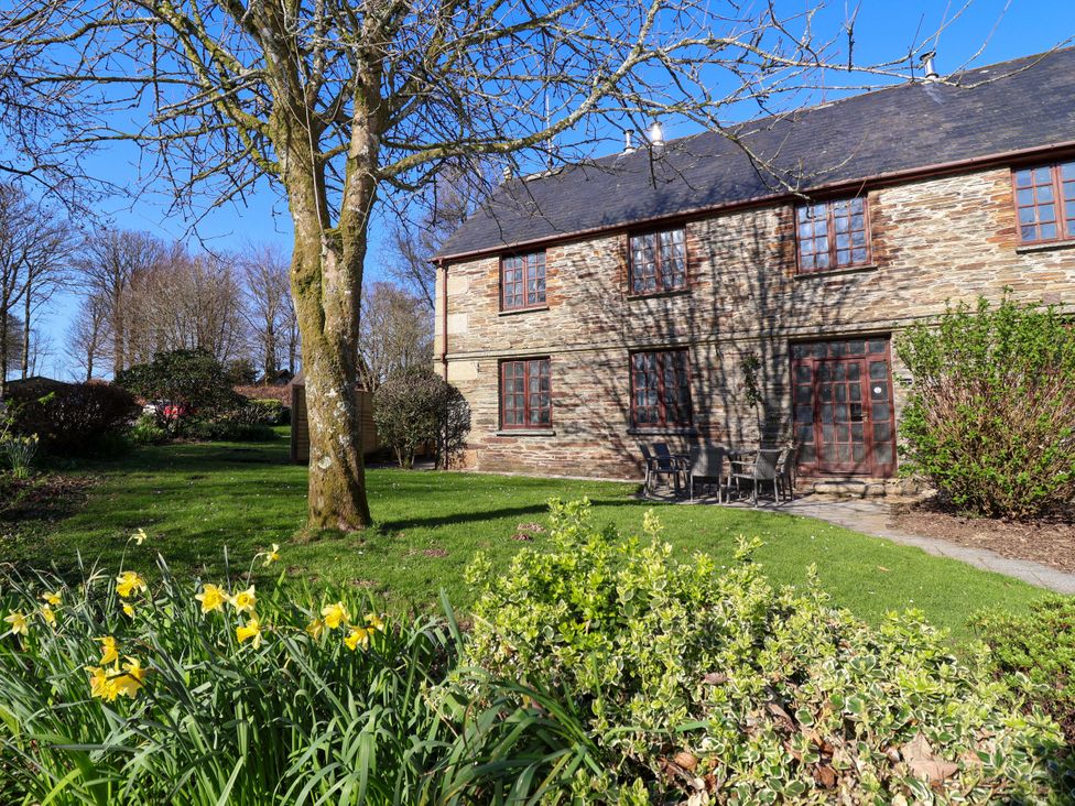 A building with chairs and a pathway surrounded by grass and flowers at Roughtor Cottage in St Tudy