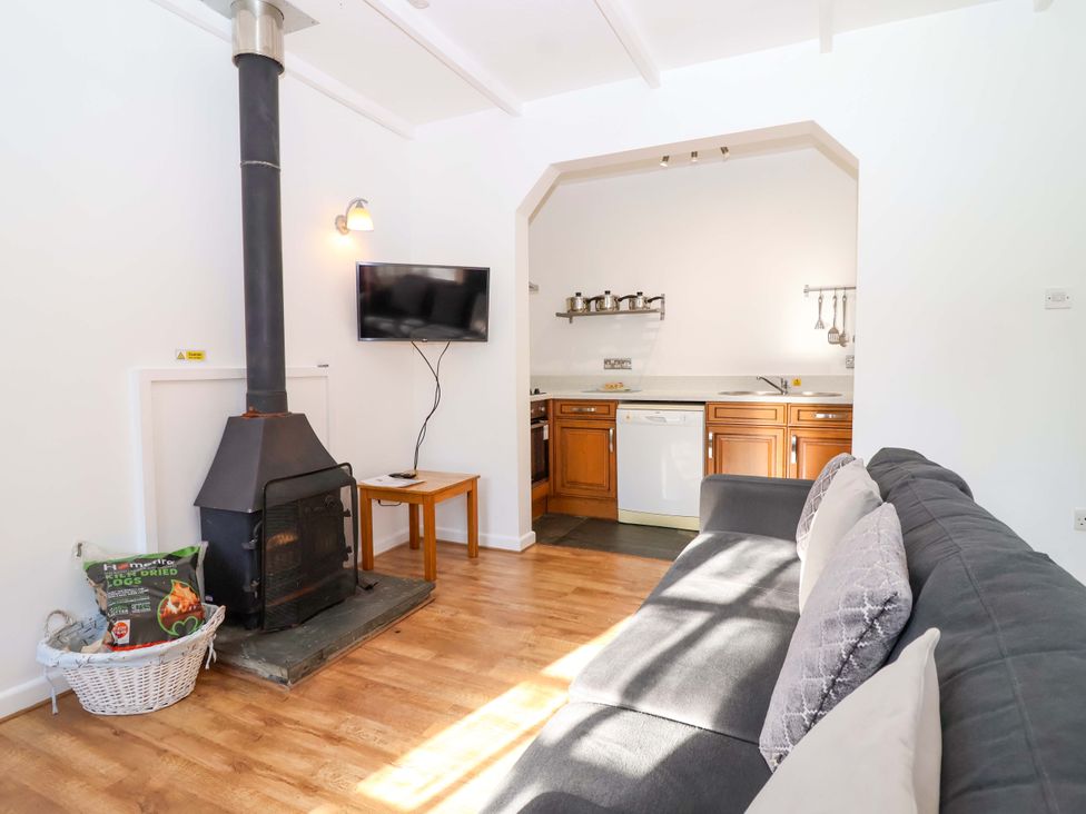 A living room with a wood stove and kitchen area at Roughtor Cottage St Tudy