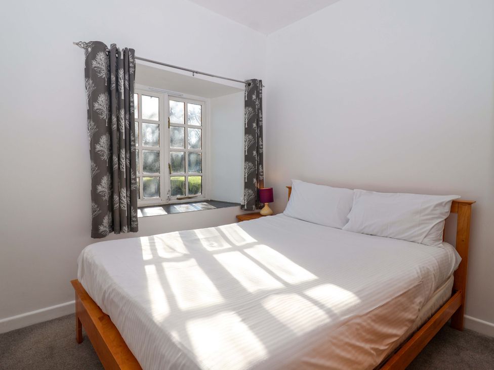 A bedroom with a bed and a window at Roughtor Cottage St Tudy