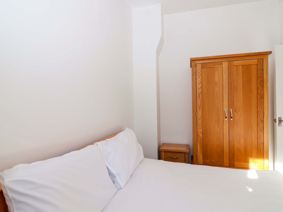 A bedroom with a bed and wooden wardrobe at Roughtor Cottage St Tudy