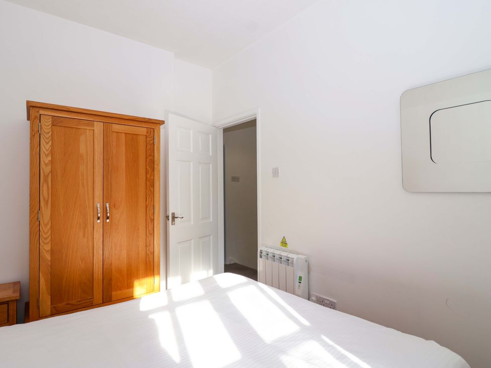 A bedroom with a wardrobe and a door at Roughtor Cottage St Tudy