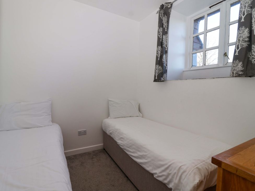 A bedroom with two beds and a window at Roughtor Cottage in St Tudy
