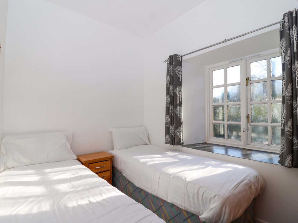 A bedroom with two beds and a window at Roughtor Cottage in St Tudy