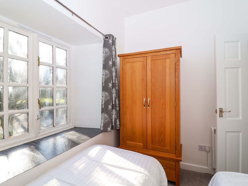 A bedroom with a wardrobe and a window at Roughtor Cottage in St Tudy