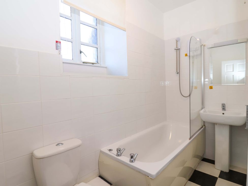 A bathroom with a bathtub, toilet, sink, and window at Roughtor Cottage in St Tudy