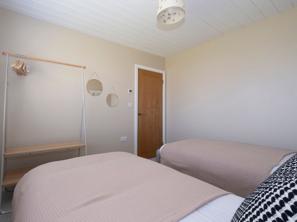 A bedroom with two beds and a wardrobe at 38 Venn Park in Stoke Fleming