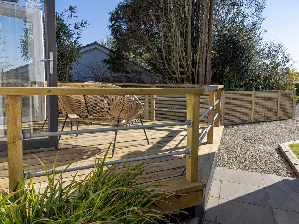 An outdoor area with a decking, rattan chair and plants at 38 Venn Park Stoke Fleming
