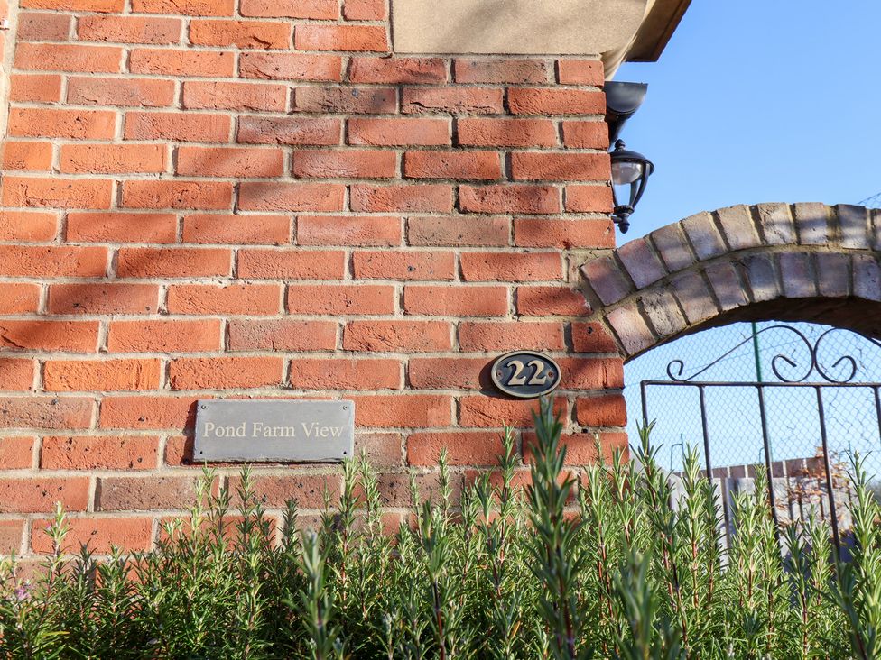 A brick wall with a nameplate and address plaque at Pond Farm View in Hinderwell