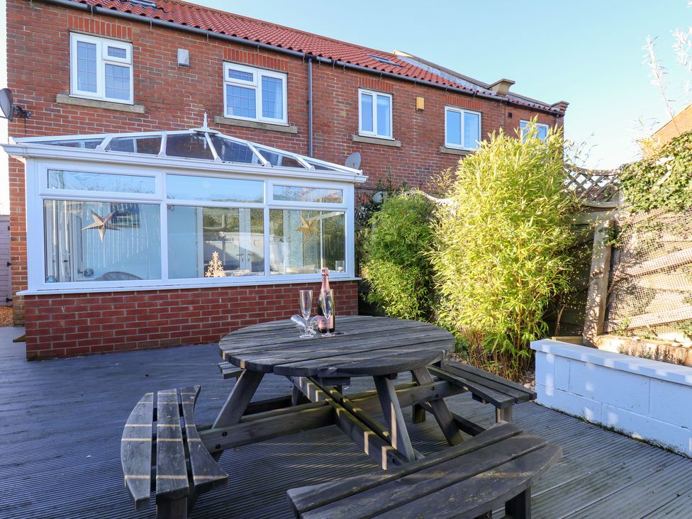 A garden with a dining table and conservatory at Pond Farm View in Hinderwell