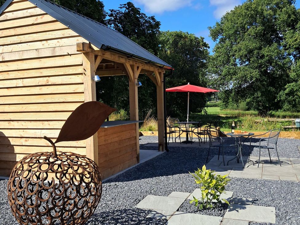 An outdoor area with a wooden structure and dining set at Dinefwr Cottage in Golden Grove near Llandeilo