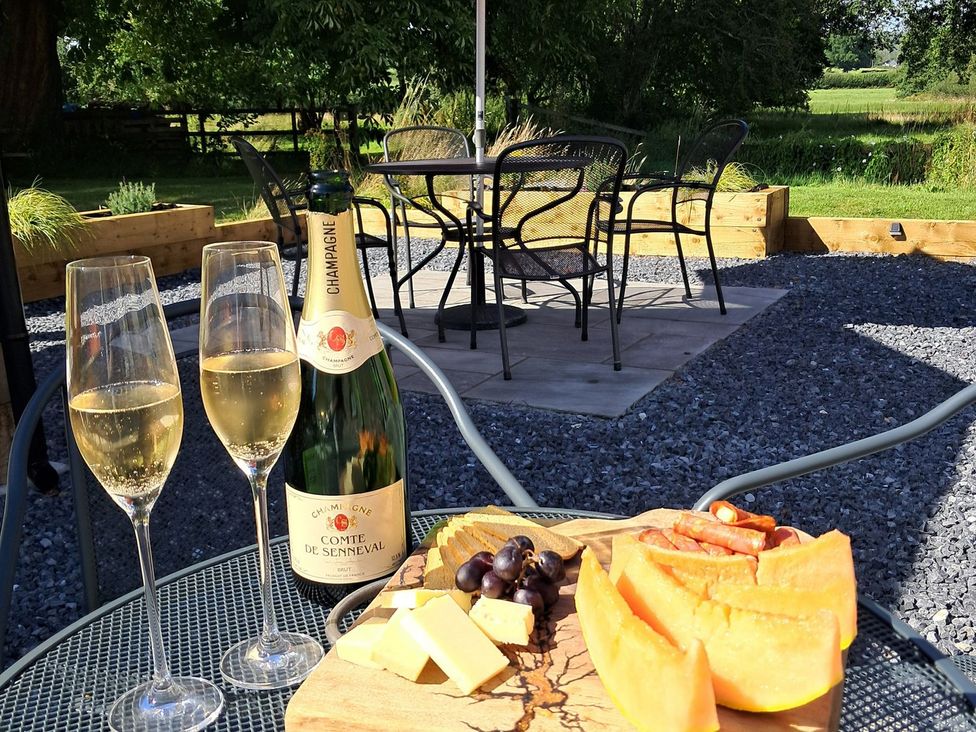 A table with champagne and food in an outdoor setting at Dinefwr Cottage in Golden Grove near Llandeilo