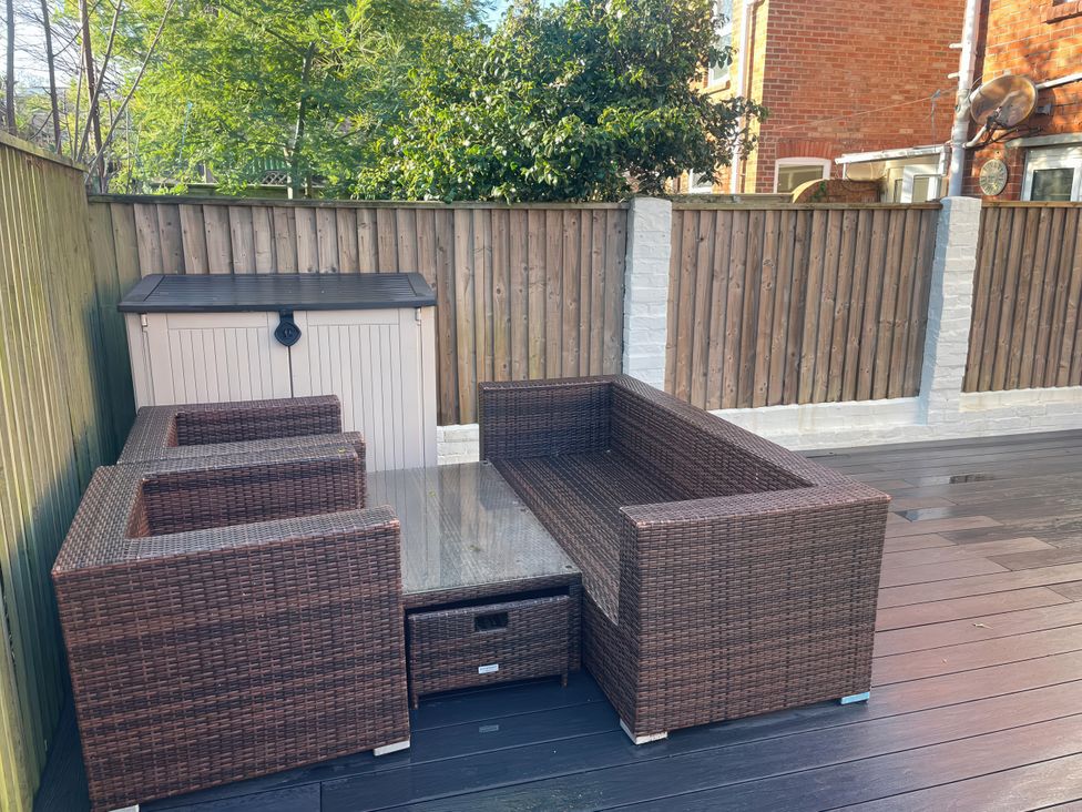 A garden with an outdoor furniture set and storage box at Owl's Rest in Weymouth