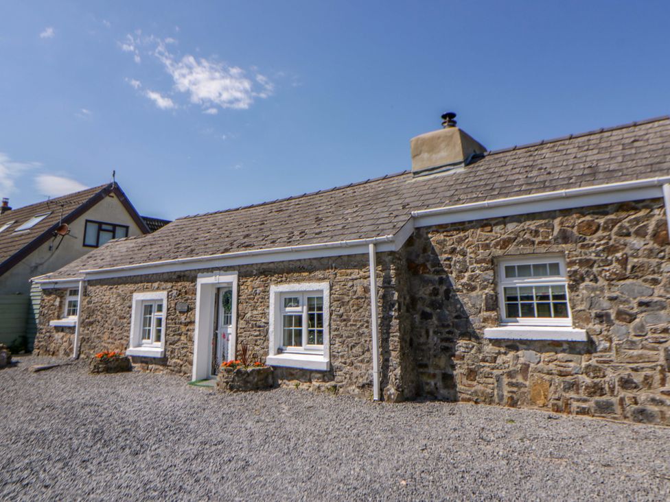 A stone cottage with a front door and windows at Cobwebs Cold Inn near Saundersfoot