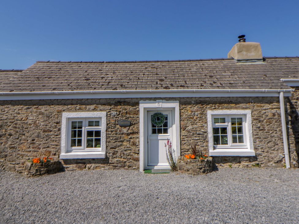 A cottage exterior with a stone wall and flower pots at Cobwebs Cold Inn near Saundersfoot