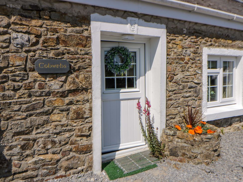 An entrance of a stone cottage with a door and planter at Cobwebs Cold Inn near Saundersfoot