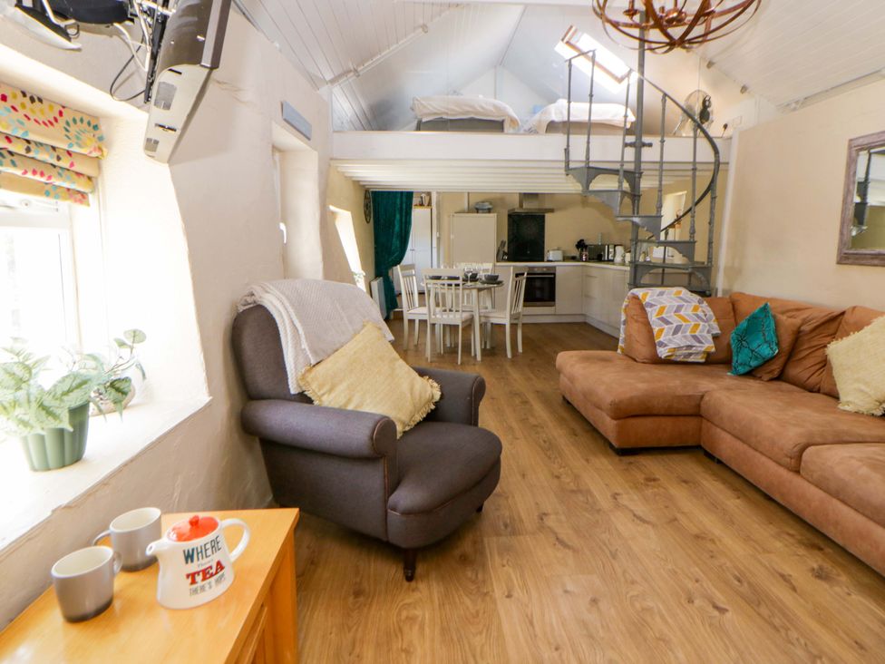 A living room with a sofa and dining area at Cobwebs Cold Inn near Saundersfoot