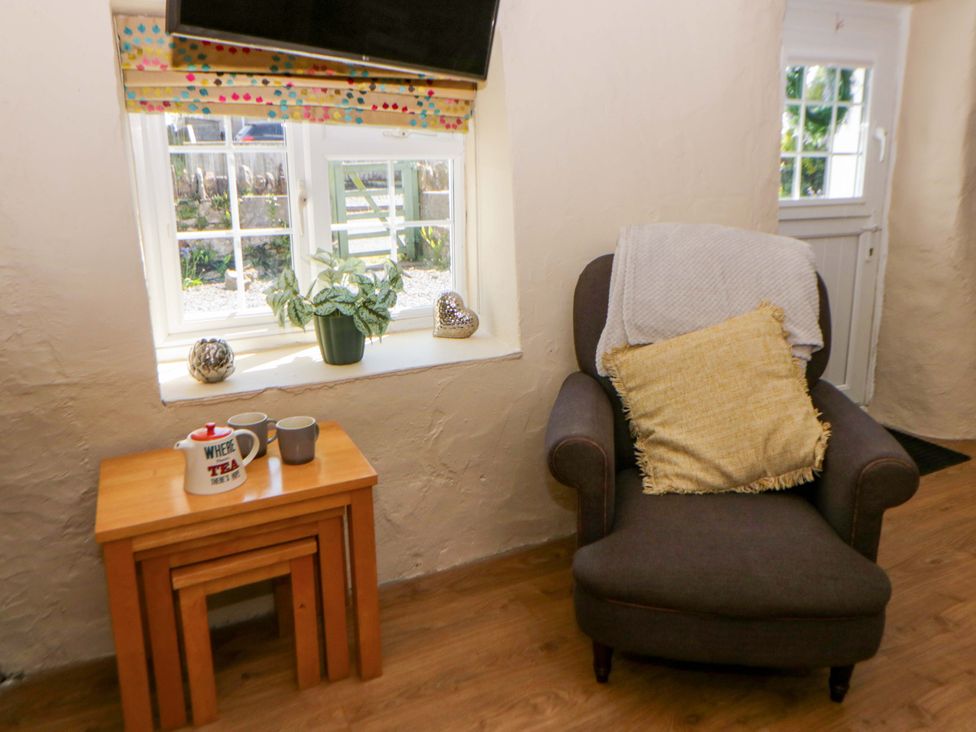 A living room with an armchair and a window at Cobwebs in Cold Inn near Saundersfoot
