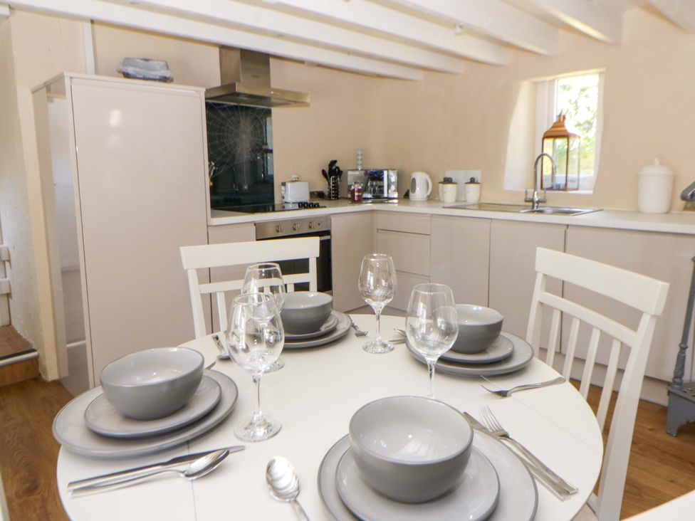 A kitchen with a dining table set with plates and glasses at Cobwebs Cold Inn near Saundersfoot