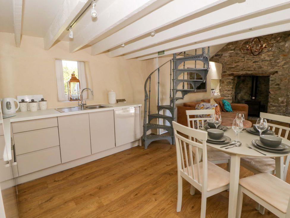 A kitchen with a dining table and spiral staircase at Cobwebs Cold Inn near Saundersfoot