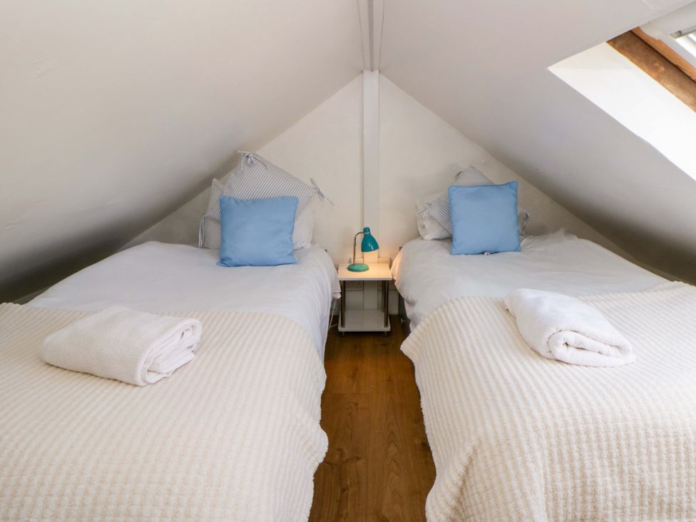 A bedroom with two beds and a lamp at Cobwebs in Cold Inn near Saundersfoot
