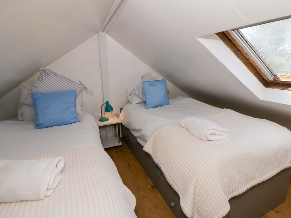 A bedroom with twin beds and a window at Cobwebs Cold Inn near Saundersfoot