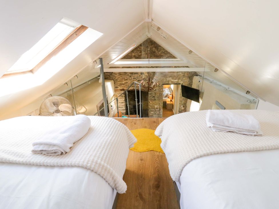 A loft with two beds and a fan at Cobwebs in Cold Inn near Saundersfoot