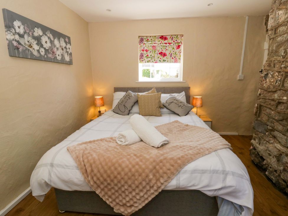 A bedroom with a bed and nightstand at Cobwebs in Cold Inn near Saundersfoot