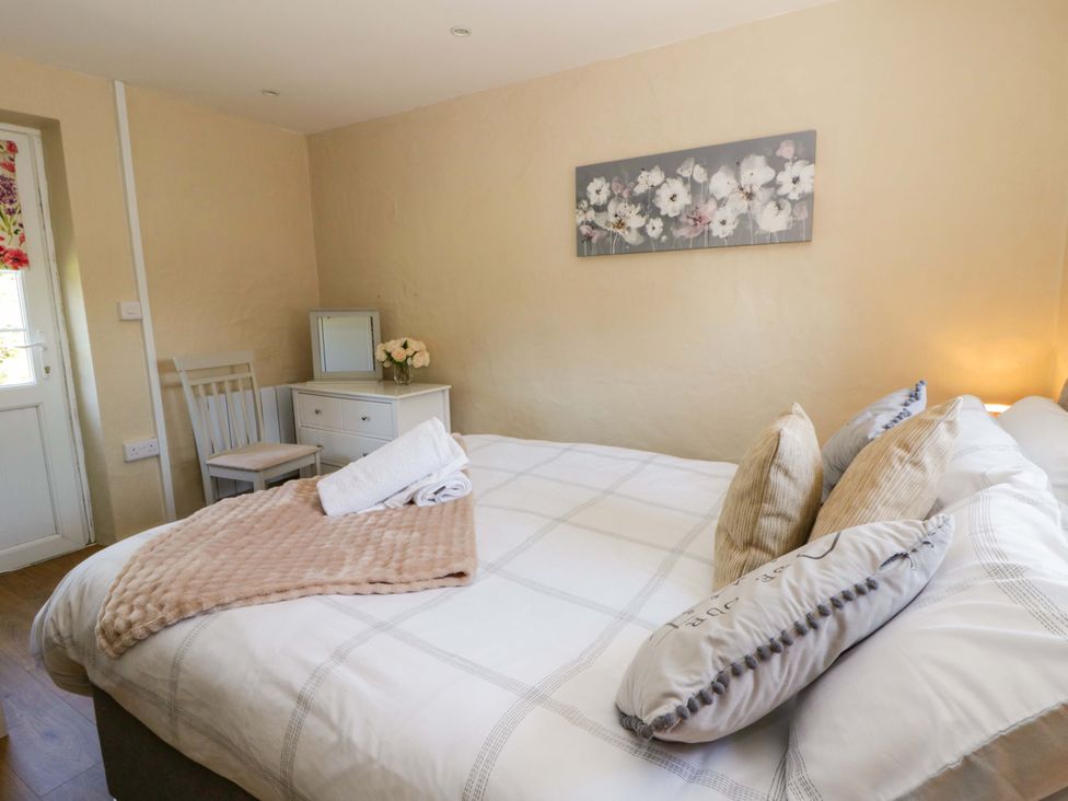 A bedroom with a bed and a chair at Cobwebs in Cold Inn near Saundersfoot