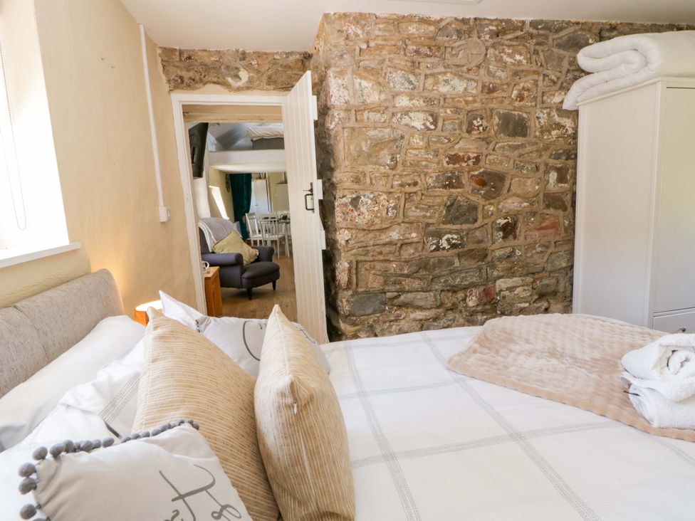A bedroom with a bed and stone wall at Cobwebs Cold Inn near Saundersfoot