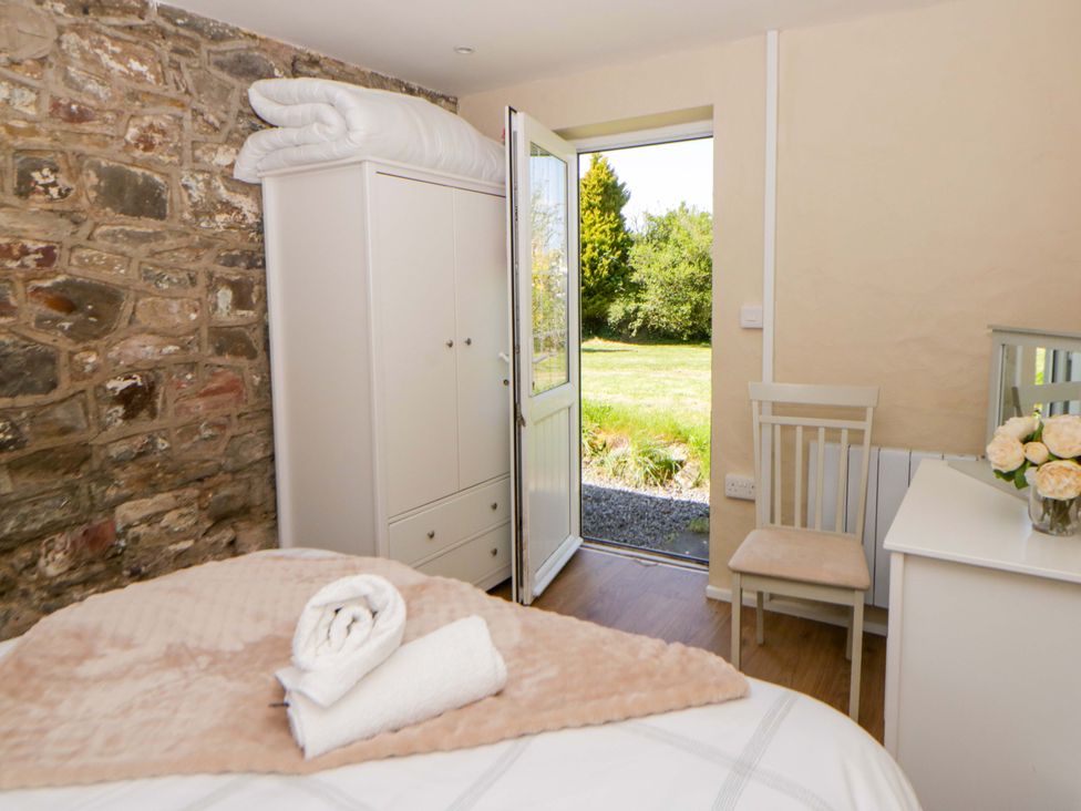 A bedroom with a bed and a door leading outside at Cobwebs Cold Inn near Saundersfoot