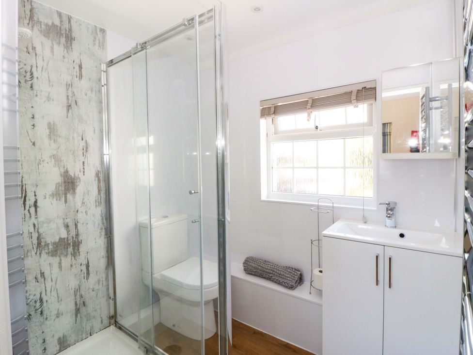 A bathroom with shower, toilet, sink and window at Cobwebs in Cold Inn near Saundersfoot