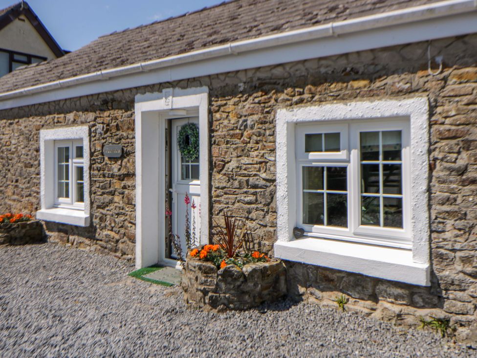 An entrance with a stone wall and flower pots at Cobwebs, Cold Inn near Saundersfoot
