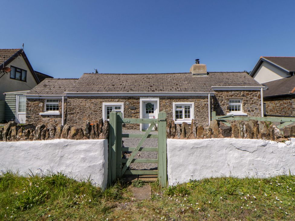 A stone cottage with a green gate at Cobwebs Cold Inn near Saundersfoot