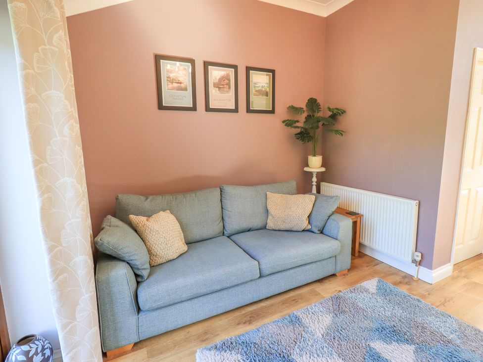 A living room with a sofa and picture frames at The Garden Suite at Fiddler Hall Barn Newby Bridge