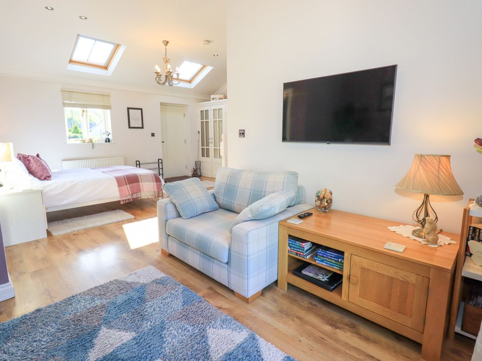 A bedroom with a bed and a couch at The Garden Suite at Fiddler Hall Barn, Newby Bridge